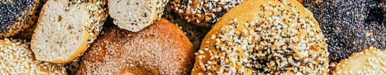 close up photo of mix of fresh bagels with seeded toppings