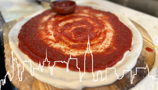 Preparing pizza, spreading sauce over the dough