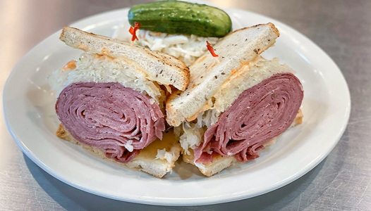 Max and Louie's plated Reuben sandwich with coleslaw and pickle